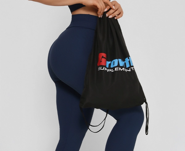 Foto de uma mulher usando legging segurando uma sacola tipo mochila da Growth Supplements