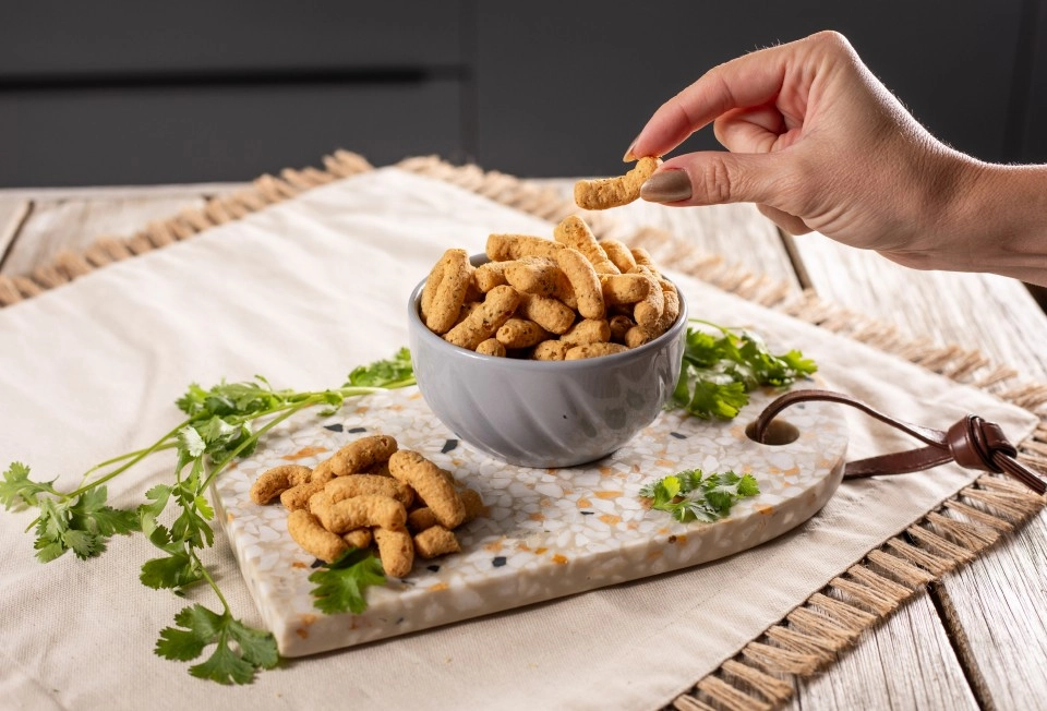 Mão de uma mulher pegando o snack Growth Protein de uma tijela